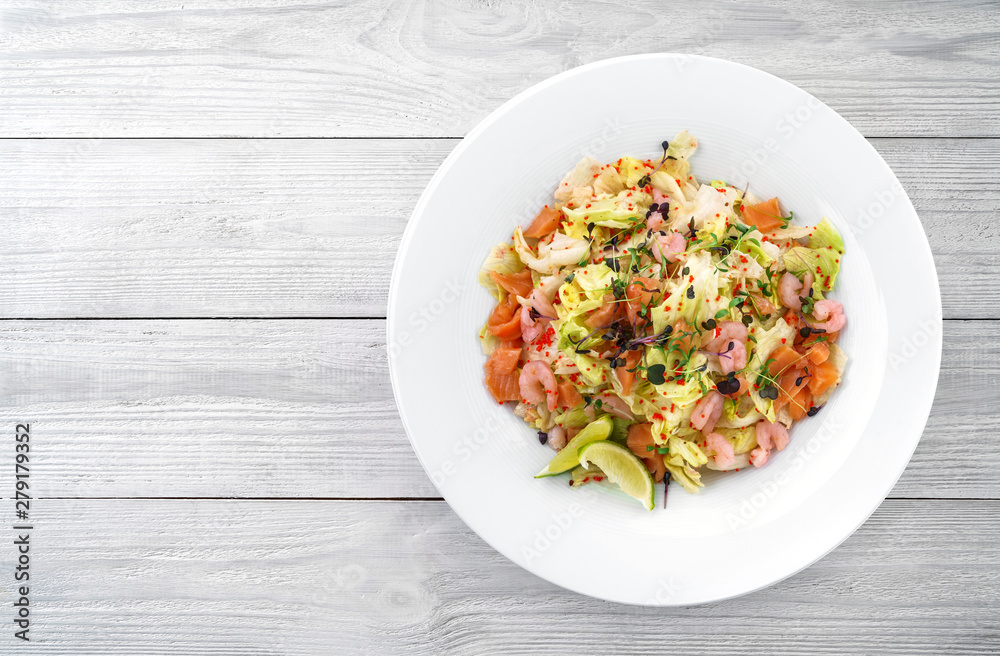Healthy fresh salad with lettuce, greens, red caviar, shrimp, fillet salmon in plate on light wooden background. Healthy food, clean eating, dieting, top view Healthy fresh salad with lettuce, greens, red caviar, shrimp, fillet salmon in plate on light wooden background. Healthy food, clean eating, dieting, top view