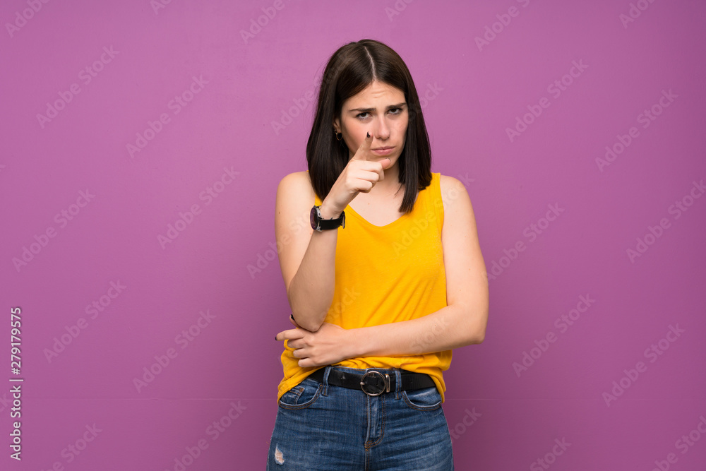 Young woman over isolated purple wall frustrated and pointing to the front Young woman over isolated purple wall frustrated and pointing to the front