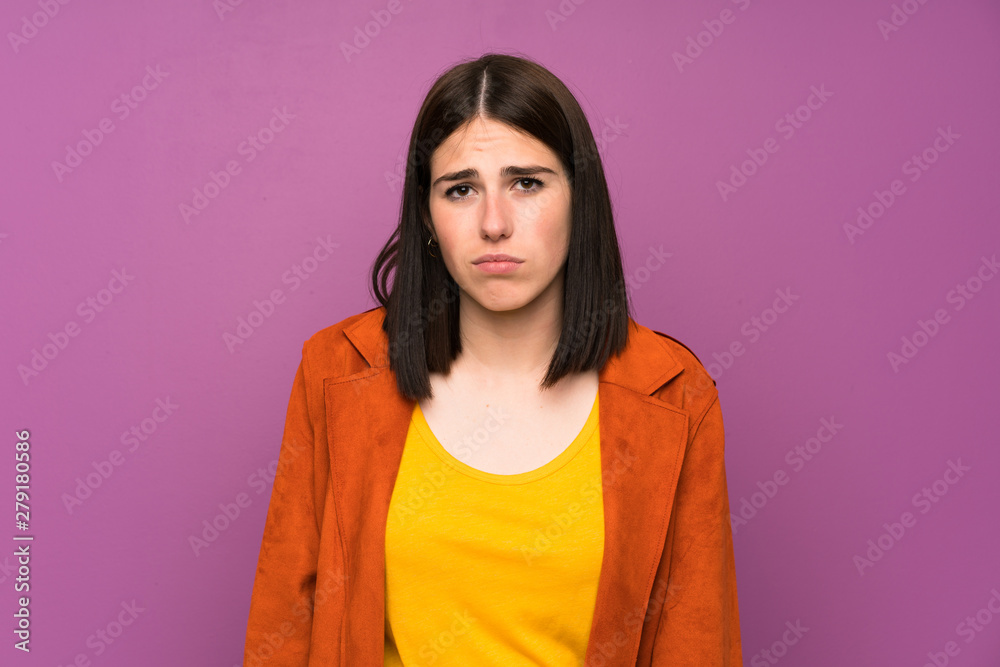 Young woman with a coat over isolated purple background sad Young woman with a coat over isolated purple background sad