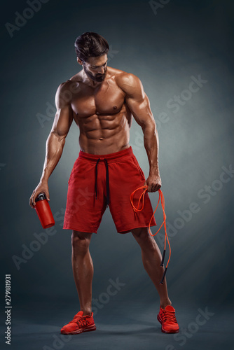 Handsome Athletic Men after Cardio Workout. Holding Jump Rope in One Hand and Proten Drink Bottle in another photo