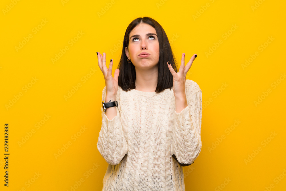 Young woman over isolated yellow wall frustrated by a bad situation Young woman over isolated yellow wall frustrated by a bad situation