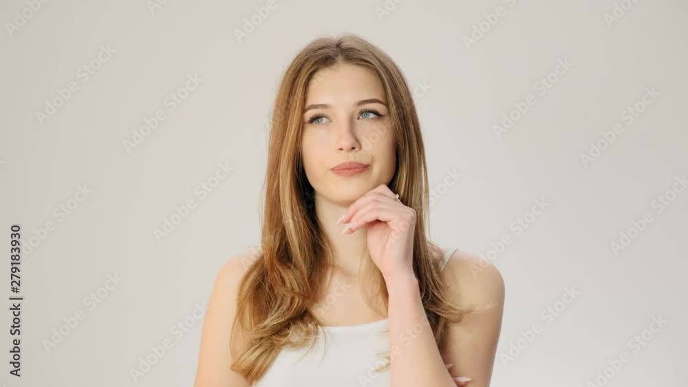 Young upset thoughtful woman smiles on the white background slow motion Young upset thoughtful woman smiles on the white background slow motion
