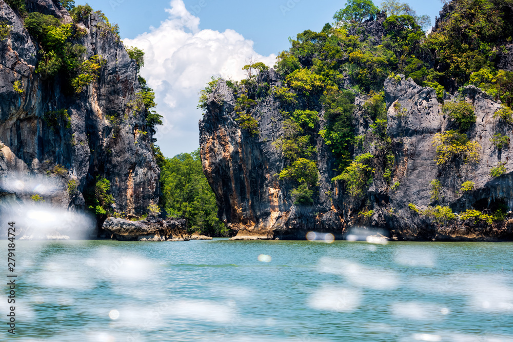 Large cliffs and mountains of islands in Phang Nga archipelago, splash of water from speed boat
