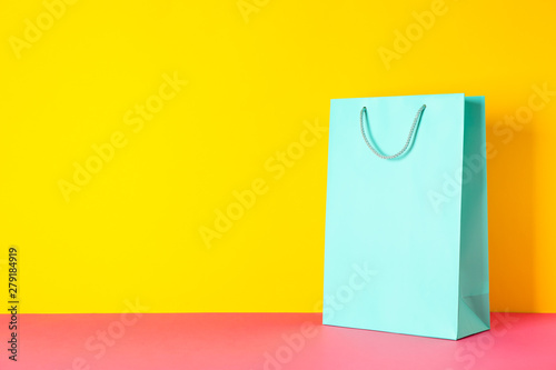 Color paper bag on pink table against yellow background, copy space