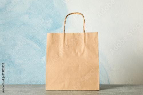 Fotografía Paper bag on grey table against blue background, copy space