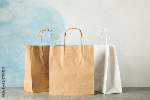 Paper bags on grey table against blue background, copy space