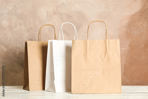Paper bags on white table against brown background, copy space