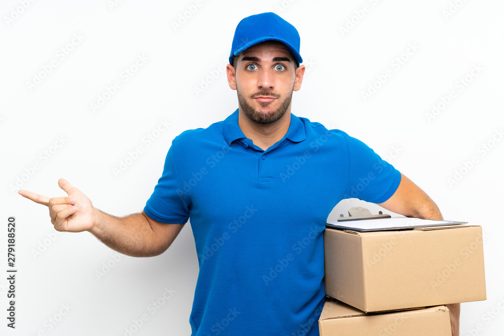 Delivery man over isolated white background pointing to the laterals having doubts