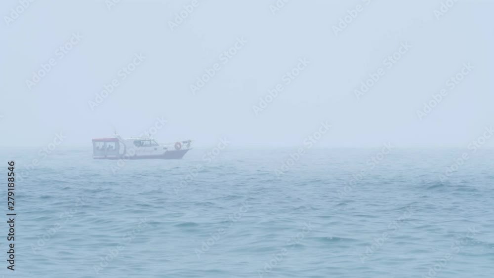 A lone motor boat with tourists or fishermen moves on the waves in the open sea in cloudy foggy weather. A lone motor boat with tourists or fishermen moves on the waves in the open sea in cloudy foggy weather.