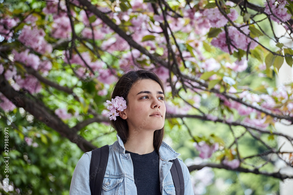 Young woman posing on the background of blooming sakura Young woman posing on the background of blooming sakura