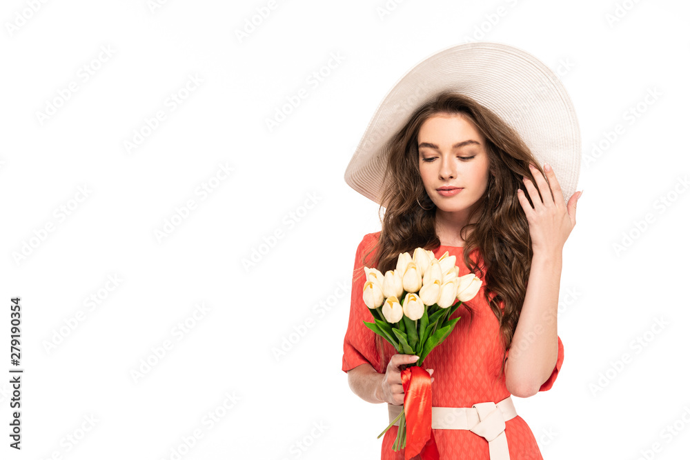 elegant woman in hat and dress looking at white tulips isolated on white