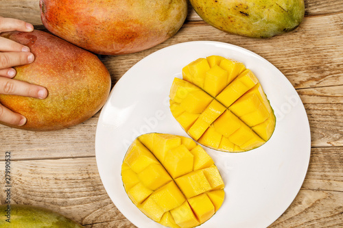 Fototapeta Naklejka Na Ścianę i Meble -  fresh juicy yellow mango with a child hand on it 