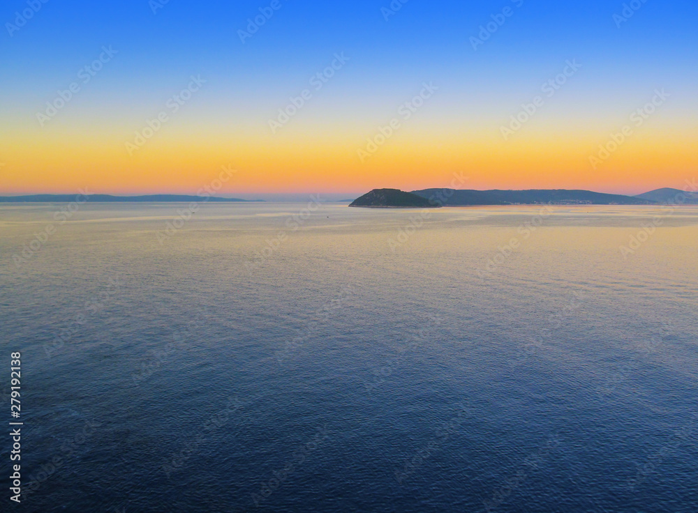 Beautiful morning panorama of Adriatic sea near Split, Croatia. A panoramic view at dawn of a water, sky with a dawning, silhouette of coastline of islands. Nautical landscape of bay in West Europe.