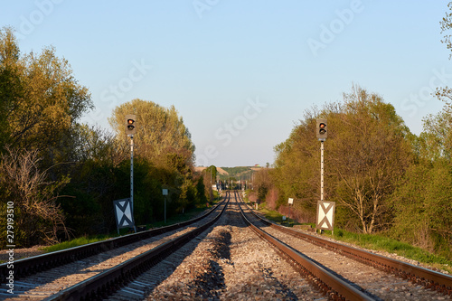 Two tracks with signal, stones and trees, under the evening sky