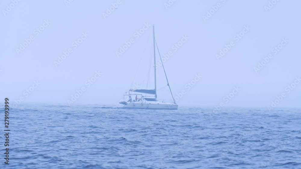 A lone motor boat with tourists or fishermen moves on the waves in the open sea in cloudy foggy weather. A lone motor boat with tourists or fishermen moves on the waves in the open sea in cloudy foggy weather.