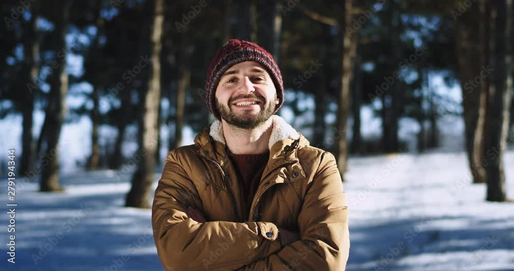 Very attractive man with a large smile looking straight to the camera and feeling excited he stand in the middle of snowy forest Very attractive man with a large smile looking straight to the camera and feeling excited he stand in the middle of snowy forest