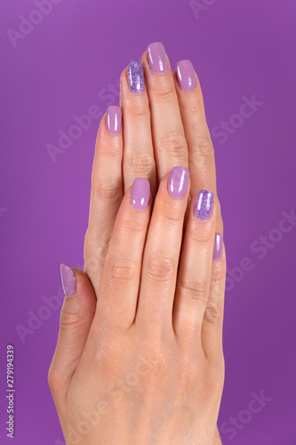 Beautiful female hands with a lilac color nails polish gel isolated on purple background in the studio. Manicure and beauty concept. Close up, selective focus
