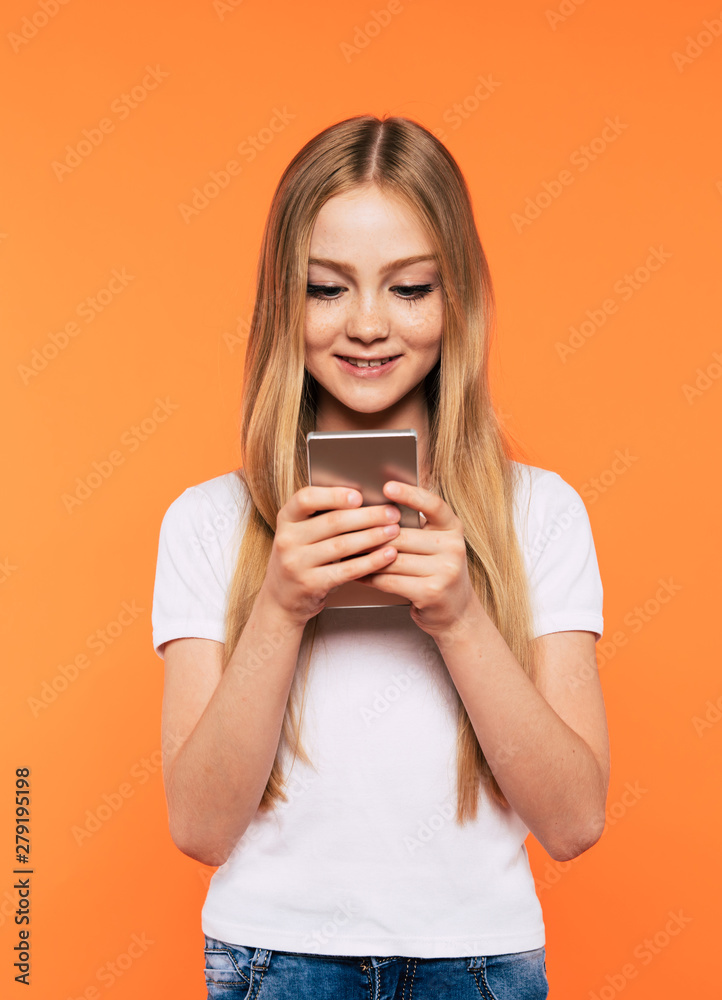 Happy attractive little blonde girl with smart phone isolated on yellow background Happy attractive little blonde girl with smart phone isolated on yellow background