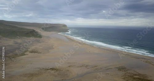 Flynig over Beach in Iceland Aerial view of Beach and large cliff in Western Fjords, Iceland photo