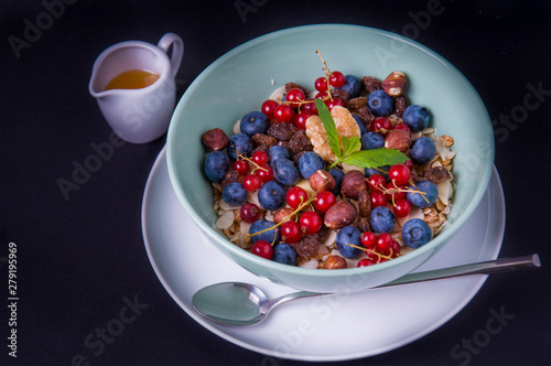 Oatmeal cereal porridge with fresh berries and nuts. Healthy breakfast. Top view on black table