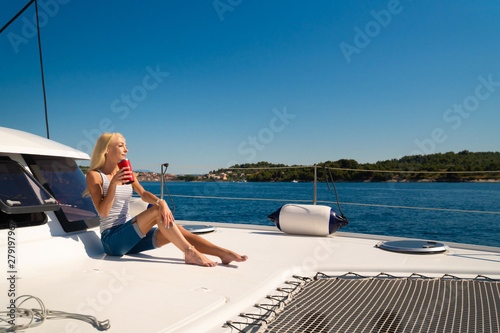 beautiful young woman in casual wear drinking tea of coffee on a yacht front