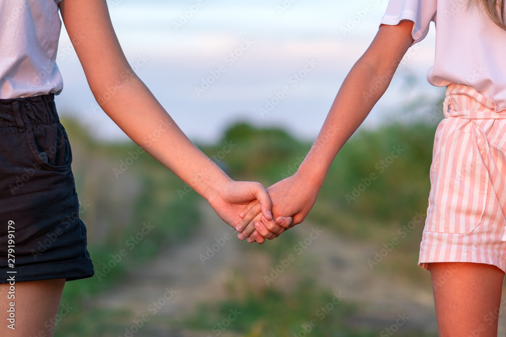 Two girl holding hand and walking on the road. Young women couple on the beautiful landscape. Two girl holding hand and walking on the road. Young women couple on the beautiful landscape.