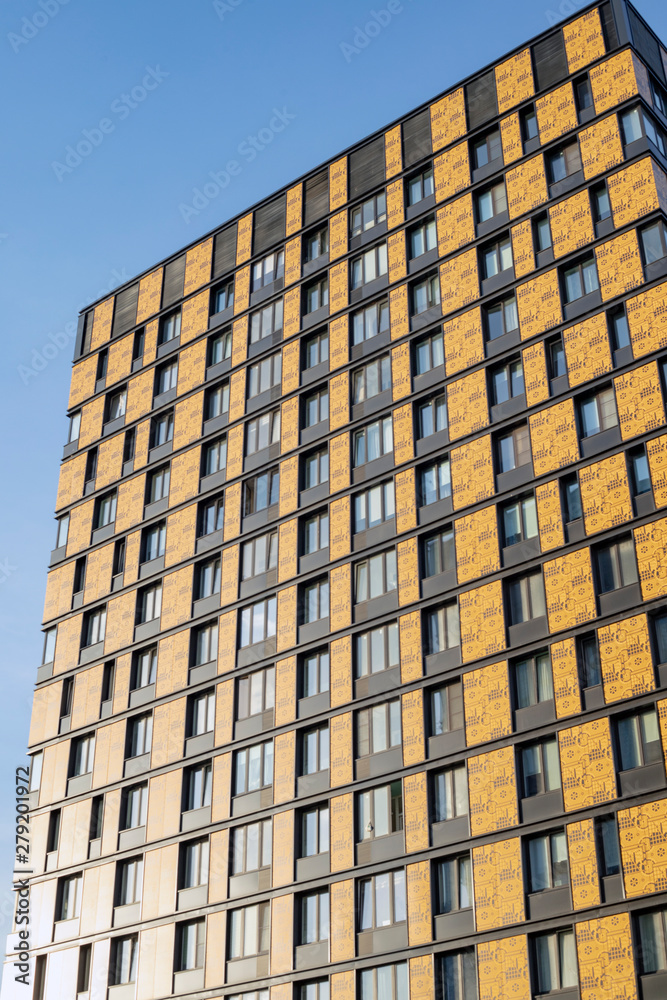 The building has a ventilated facade, against a clear blue sky. Urban development and architecture of glass and concrete. The building has a ventilated facade, against a clear blue sky. Urban development and architecture of glass and concrete.
