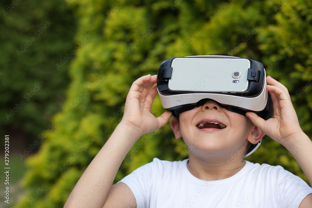 Cute little boy using VR glasses outdoors in a park - Blogger testing augmented reality goggles concept - Gamer exulting during 3D video game playing 