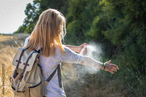 Woman tourist applying mosquito repellent on hand during hike in nature. Insect repellent. Skin protection against tick and other insect. photo