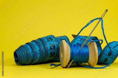 Blue thread, tape measure and sewing needle