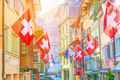 Old street with old colorful buildings with bay window balconies decorated with national flags, Zurich, Switzerland
