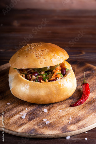 Homemade food. Bun stuffed with meat and vegetables in wooden plate on wooden table