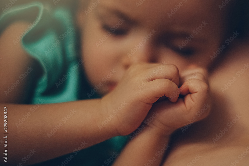 Adorable little girl sleeping in a bed with parents in a room with lights off her palms are folded together in the form of a heart, selective focus, noise effect Adorable little girl sleeping in a bed with parents in a room with lights off her palms are folded together in the form of a heart, selective focus, noise effect