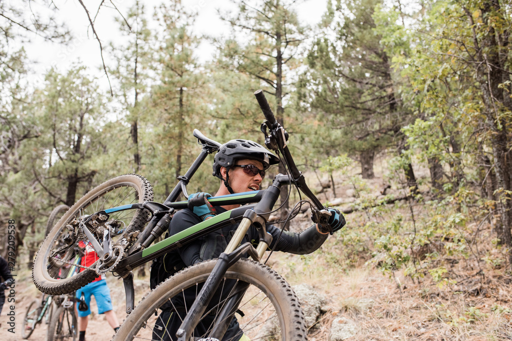 Male mountain biker carying bike up rocky trail Male mountain biker carying bike up rocky trail