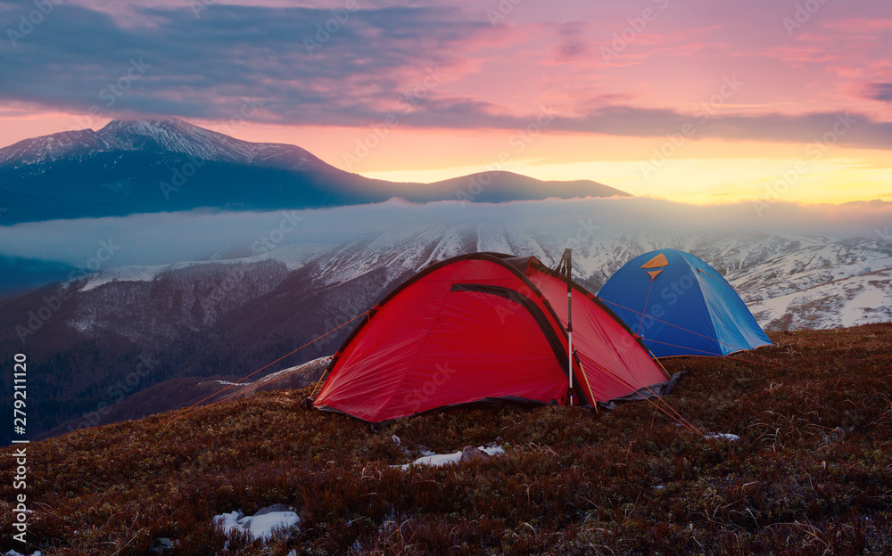 Tourist camping in autumn mountains. Two tents on nacbkground of sunrise