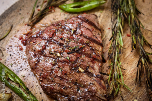 Roast beef on a chopping Board with rosemary and green hot pepper.