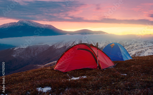 Tourist camping in autumn mountains. Two tents on nacbkground of sunrise