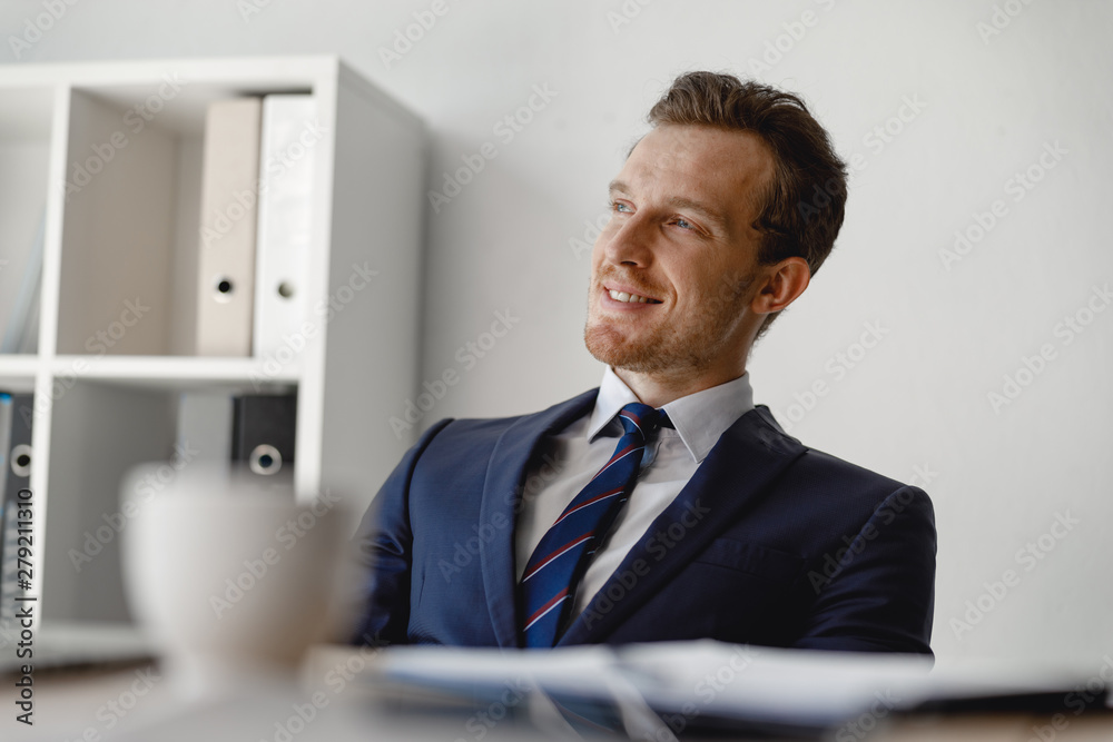 Cheerful man in suit and tie looking away and smiling