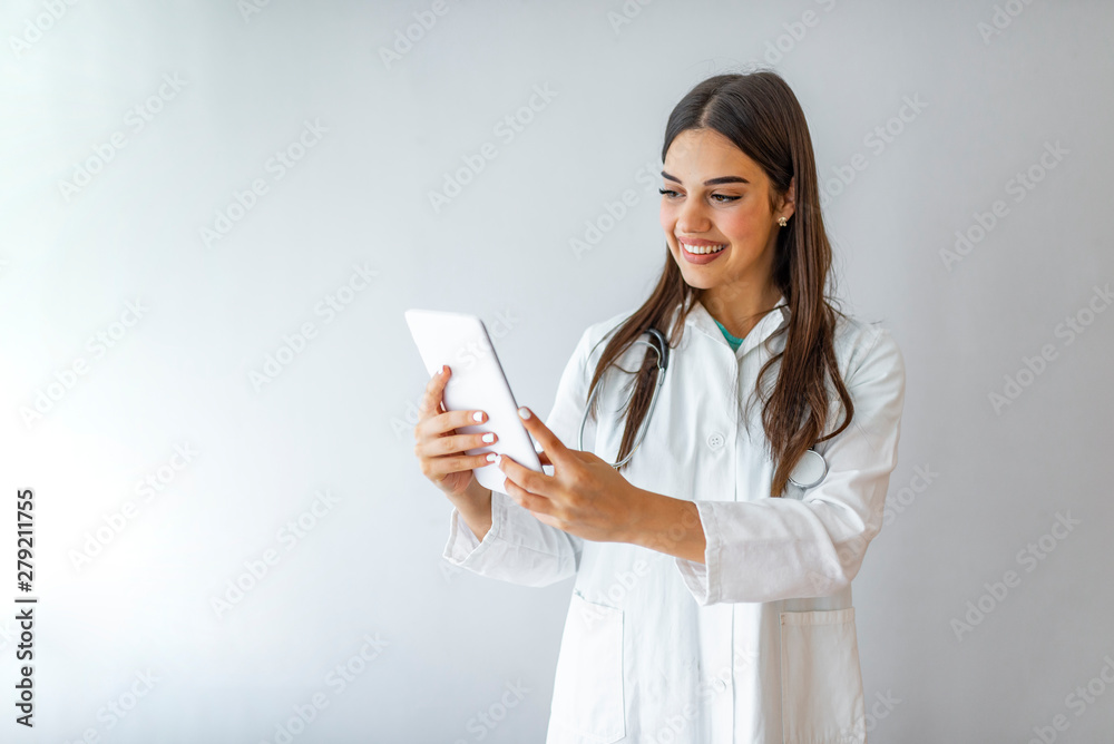 Woman doctor with stethoscope write on tablet at hospital ,isolated on grey. Doctor with tablet computer. Isolated over grey background. Portrait of a nurse using a digital tablet. Large copy-space Woman doctor with stethoscope write on tablet at hospital ,isolated on grey. Doctor with tablet computer. Isolated over grey background. Portrait of a nurse using a digital tablet. Large copy-space