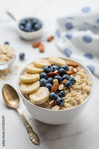Oatmeal porridge with blueberries, almonds and banana on marble table photo