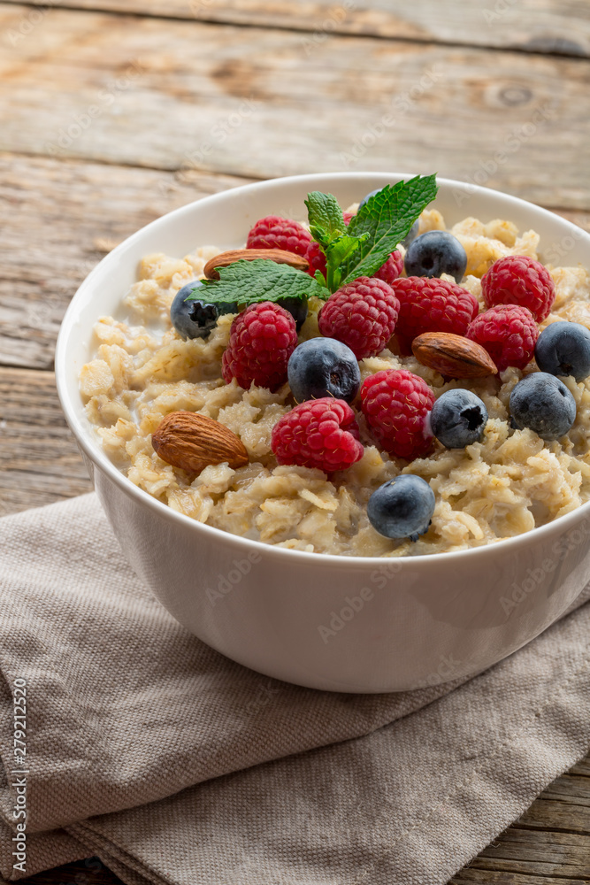 Oatmeal with raspberries, almonds and blueberries and mint on old wood background Oatmeal with raspberries, almonds and blueberries and mint on old wood background
