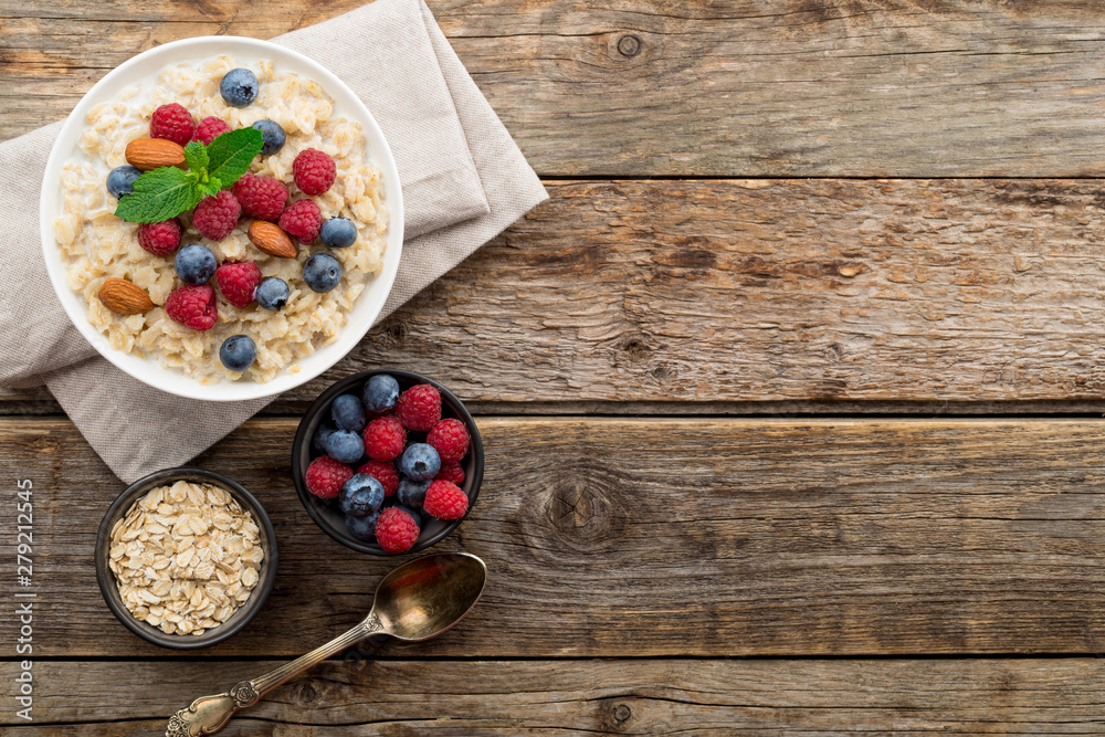 Oatmeal with raspberries, almonds and blueberries and mint on old wood background Oatmeal with raspberries, almonds and blueberries and mint on old wood background