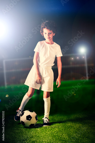 Soccer, action, ball. Portrait of soccer player hitting the ball on night stadium background