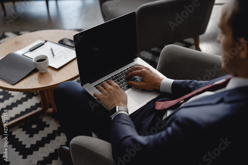 Businessman in hotel hall with laptop and documents on the background