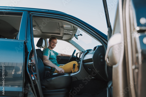Joyful young man sitting in his car