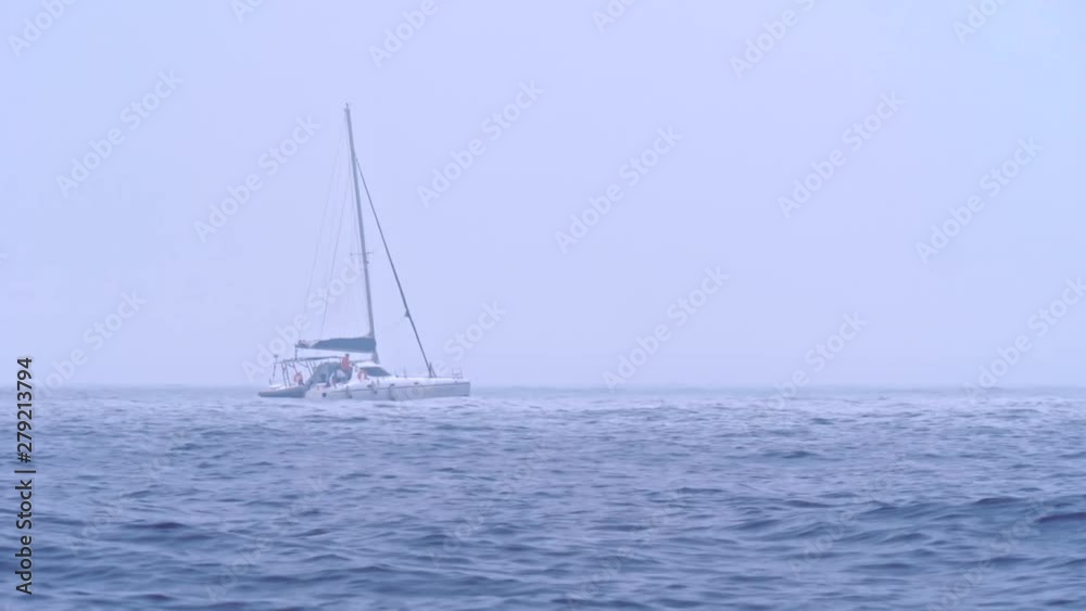 A lone motor boat with tourists or fishermen moves on the waves in the open sea in cloudy foggy weather. A lone motor boat with tourists or fishermen moves on the waves in the open sea in cloudy foggy weather.