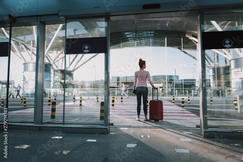 Young woman with travel luggage bag standing in airport