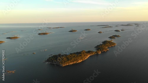 Aerial, tracking, drone shot of a group of small islands, in the Finnish archipelago, on the Gulf of Finland, at sunset, on a sunny, midsummer evening, at Porkkalanniemi, in Uusimaa, Suomi photo
