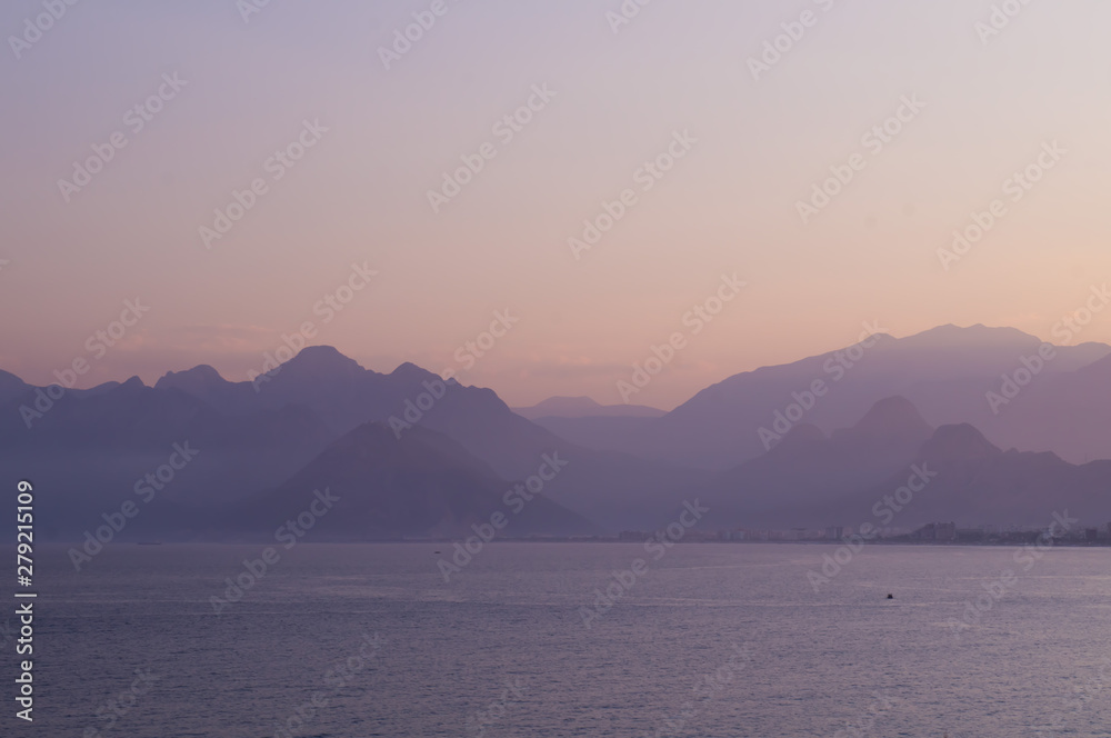 Mountains in a blue haze and sunset over the sea