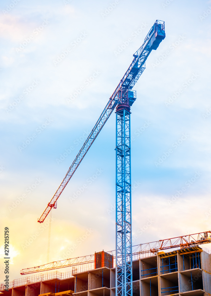 Construction cranes on blue sky with sunset background.
